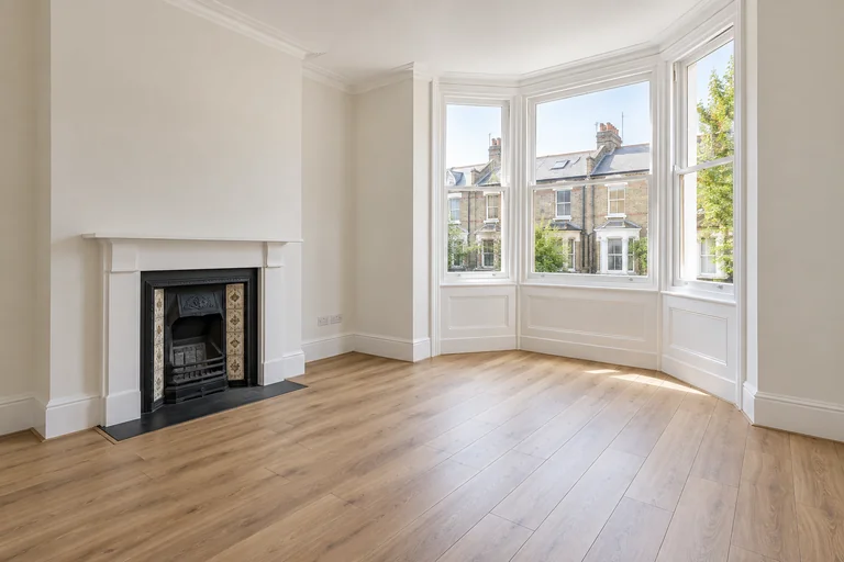 Refurbished empty room with a bay window and timber flooring.