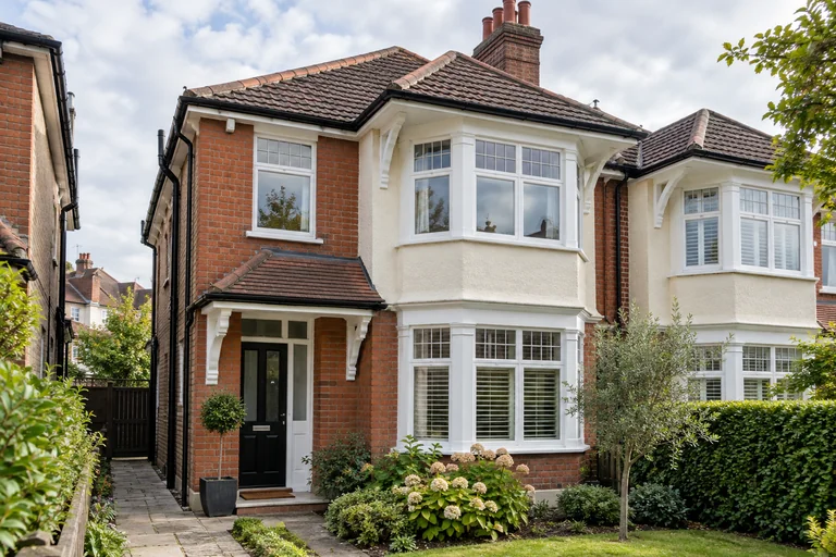Edwardian semi-detached house showing roof, guttering and rendered bay window.